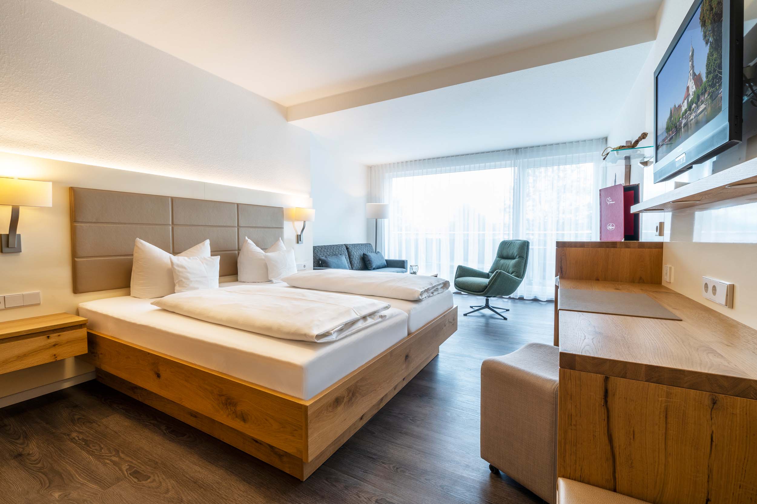 Helles, modernes Hotelzimmer mit Doppelbett und Fernseher.