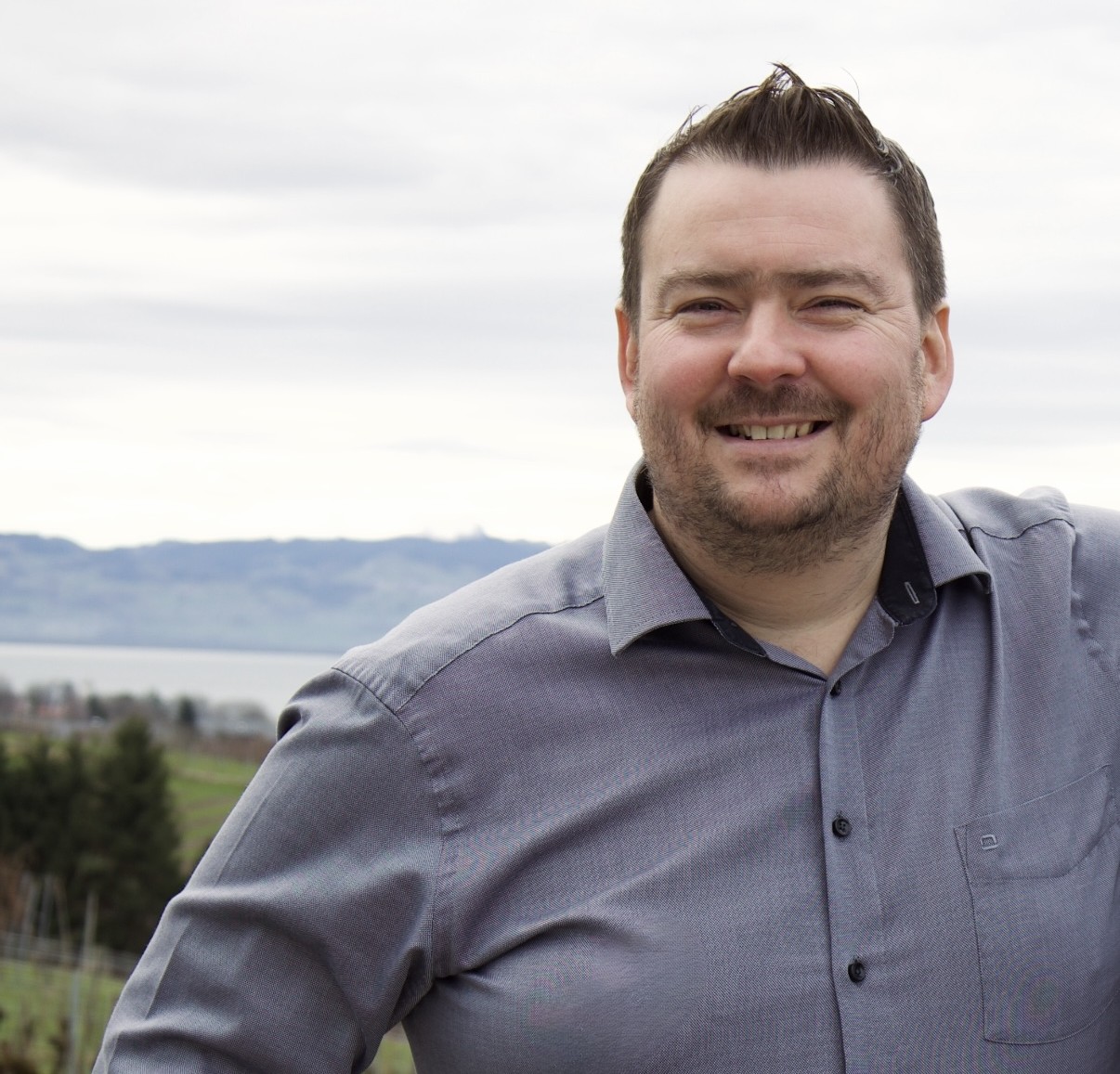 Lächelnder Mann auf einem landschaftlichen Hintergrund