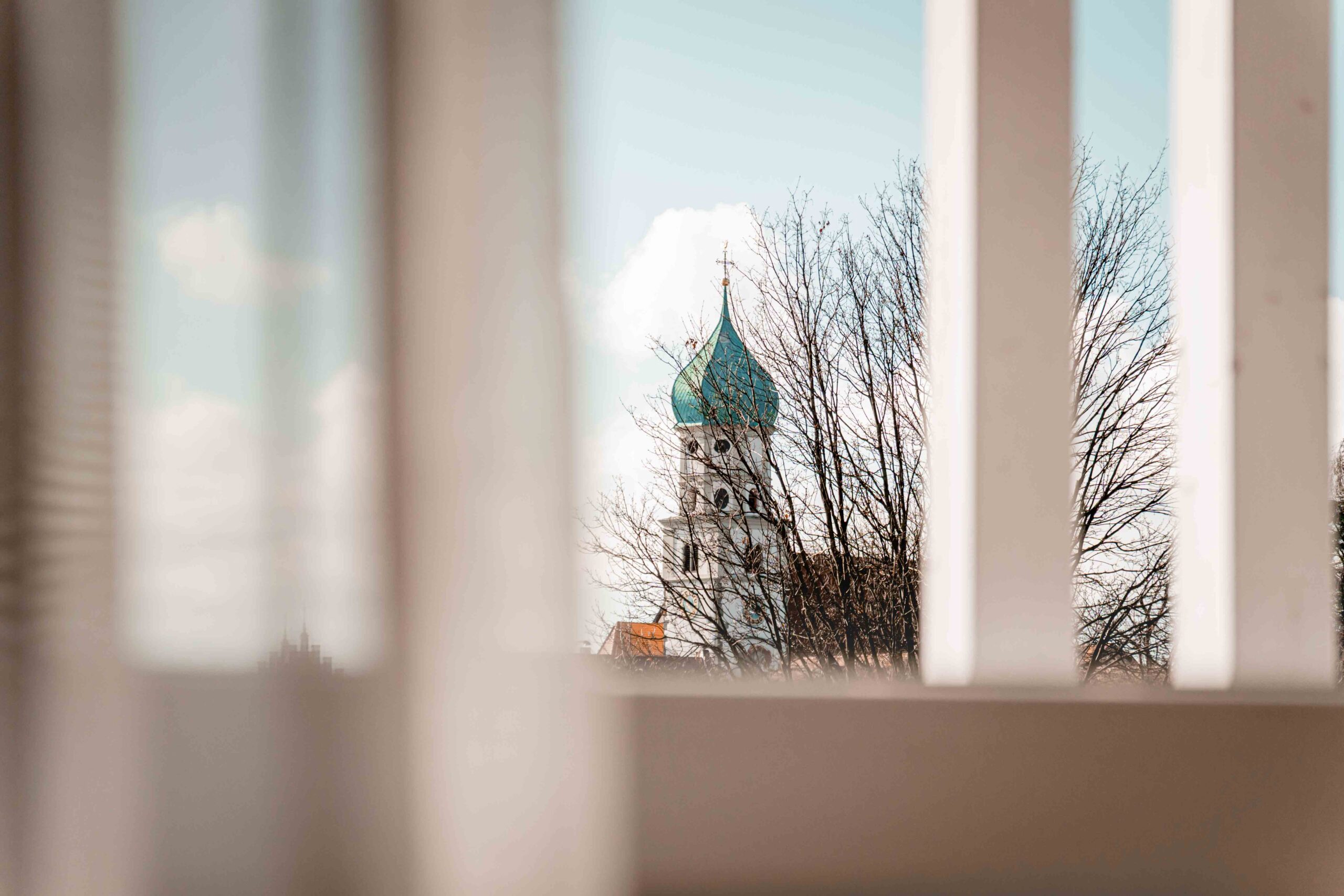Blick auf einen Kirchturm durch Fensterläden