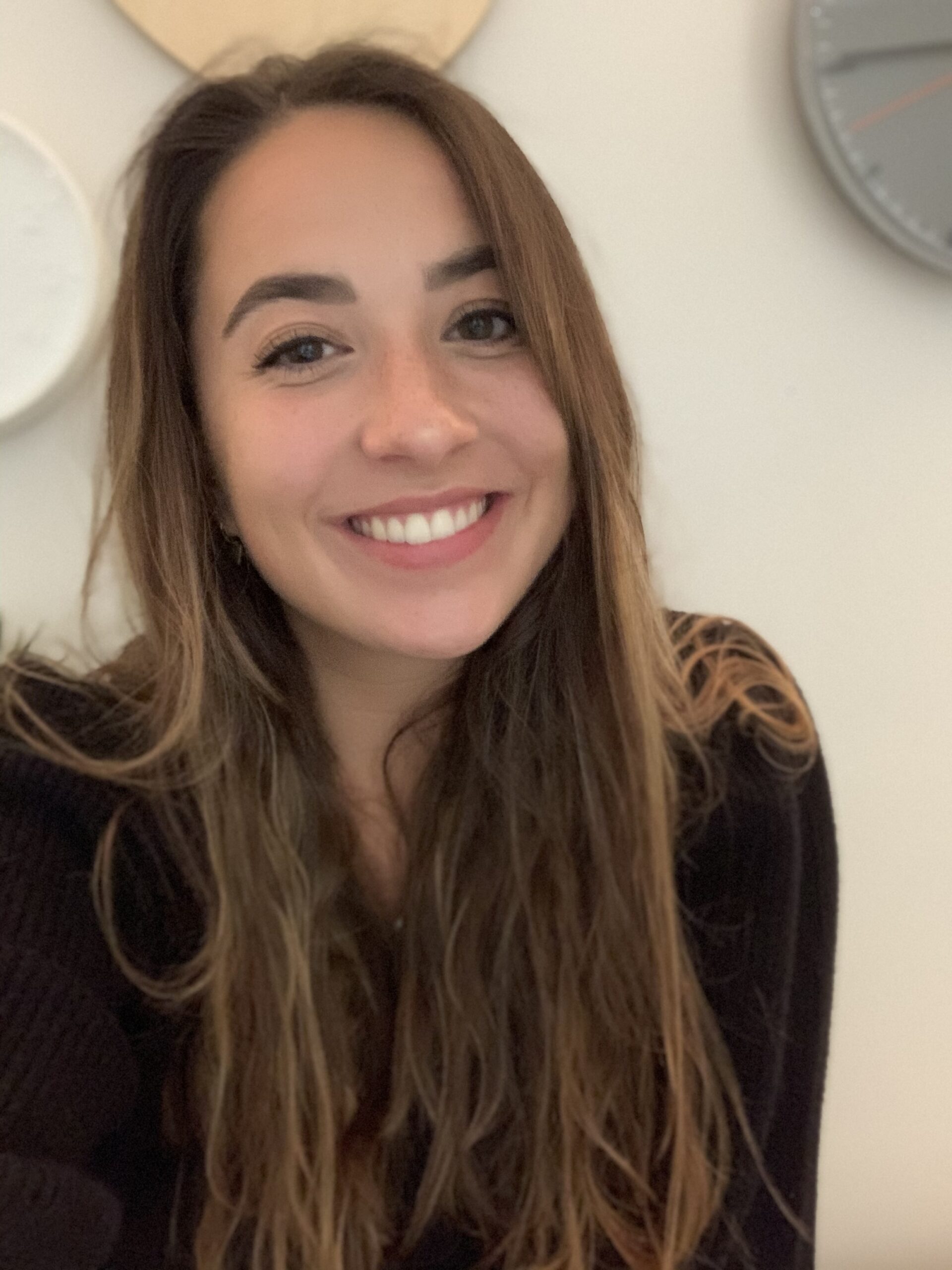 Lächelnde Frau mit langen Haaren vor Wand