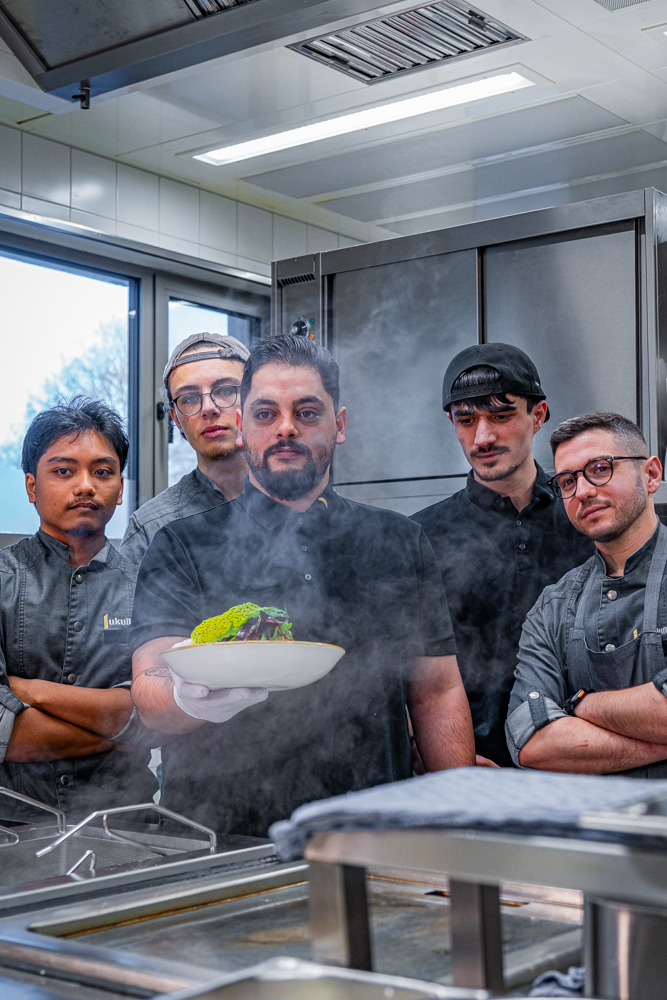 Köche präsentieren ein Gericht in einer Küche.